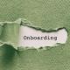 A green textured piece of paper. In the middle it's ripped open. Underneath is a piece of white paper that says "Onboarding"